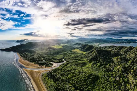 Luftaufnahme von der Küste von Costa Rica mit Meer, Strand und Regenwald unter blauem Himmel