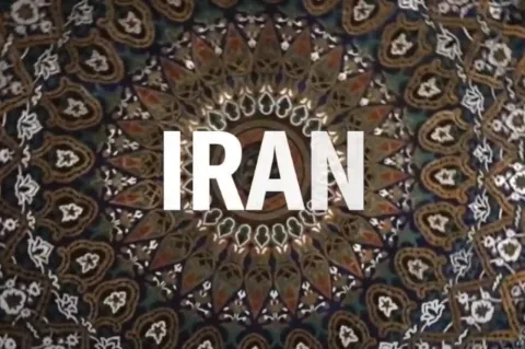 Vor einem runden, braunen, gemusterten Hintergrund steht in weißen Buchstaben der Begriff Iran.