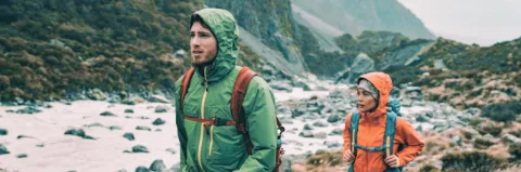 Ein Mann und eine Frau mit Rucksäcken und Regenkleidung in einer Bergumgebung