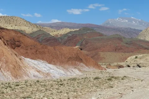 Auf einer Hochebene sind bunte Gipfel. Die Landschaft ist weitestgehend trocken.