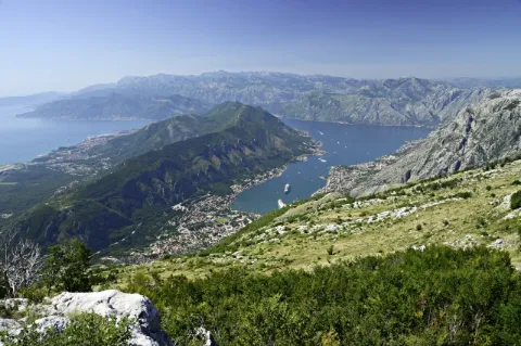Eine Bucht, umgeben von grün bewachsenen Bergen. In der Bucht ist eine kleine Stadt.