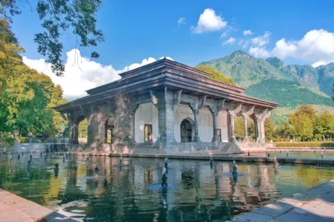 Blick auf einen Tempel der auf dem Wasser liegt. Im Hintergrund sind Berge zu sehen.