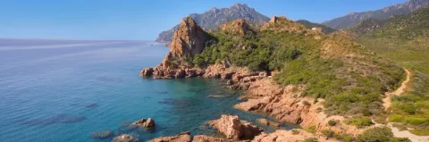 Die felsige und grün bewachsene Küste Baia di Gairo am klaren Meer von Sardinien. 