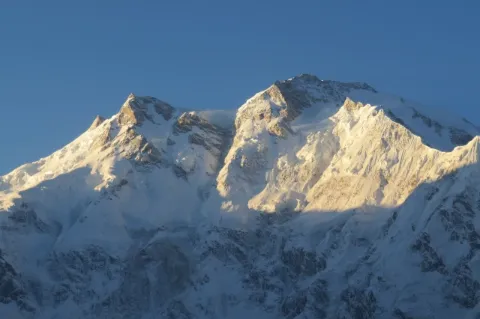 Zwei schneebedeckte Gipfel werden bis zur Hälfte von der Sonne angestrahlt.