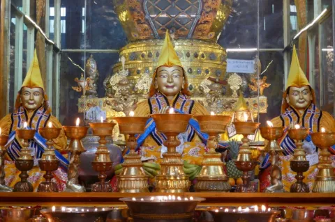 In einem Kloster sind drei Buddha Statuen. Es wirkt prunkvoll, da viel Gold verarbeitet ist.