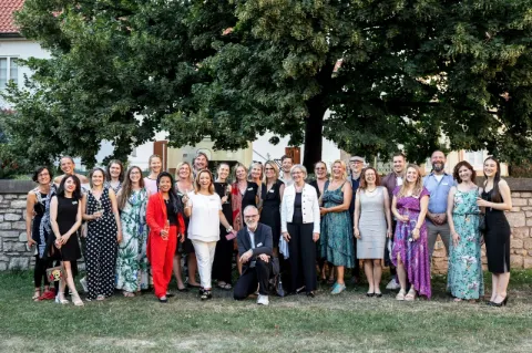 Das Hauser Team steht in festlicher Kleidung vor einem grünen Naturhintergrund