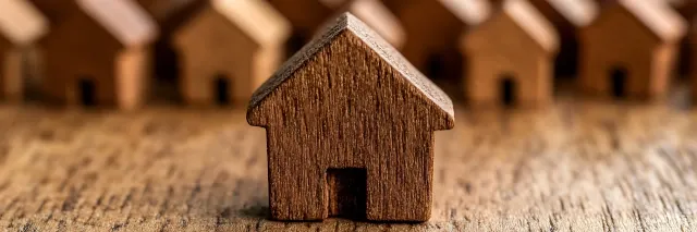 Ein kleines geschnitztes Holzhaus steht auf einer Holzunterlage.