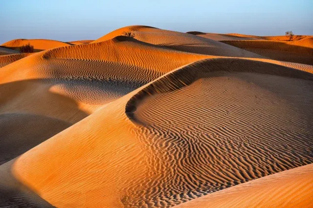 Sanddünen bei Sonnenuntergang unter blauem Himmel