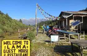 Eine Lodge im nepalesischen Mangengoth mit bunten Fahnen vor einem Bergpanorama ist zu sehen.