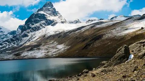 Ein ruhiger Bergsee am Fuße eines schneebedeckten Gipfels.