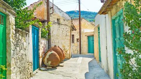 Eine traditionelle Gasse mit Steinhäusern und Tonkrügen.