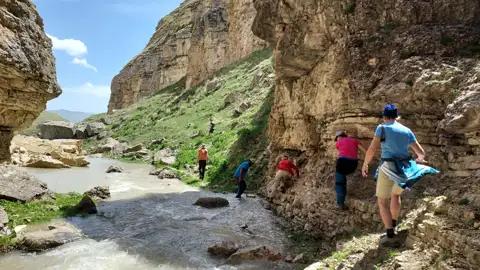 Wanderer auf einem Pfad entlang eines Flusses in einer Schlucht.