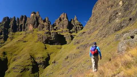 Wanderer auf einem Bergpfad mit Blick auf Felsformationen.