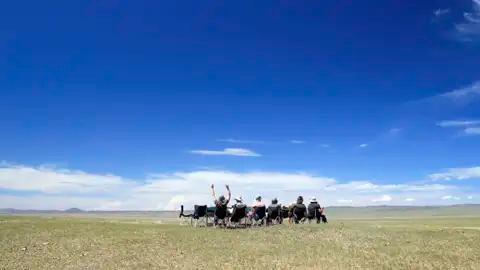 Reisende entspannen sich in Campingstühlen und genießen die Aussicht auf die weite Landschaft.