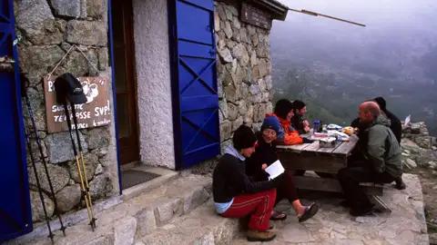 Wanderer pausieren an einer Berghütte und erfrischen sich.