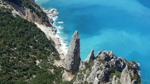 Felsige Küste mit türkisfarbenem Meer.