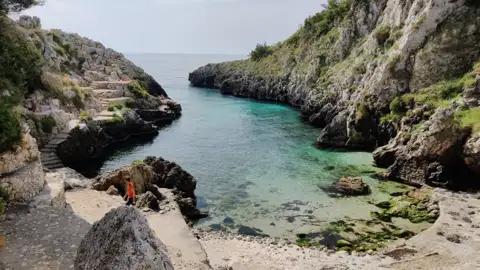 Klares, türkisfarbenes Wasser in einer felsigen Bucht.