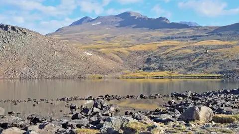 Bergsee mit felsigem Ufer und Blick auf das Bergmassiv.