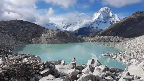 Türkisfarbener Bergsee mit schneebedeckten Gipfeln im Hintergrund.