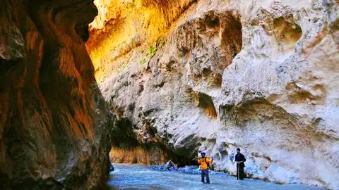 Wanderer durchqueren eine Schlucht mit einem Fluss.
