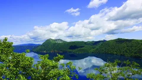 Panoramablick auf einen ruhigen See und grüne Hügel.