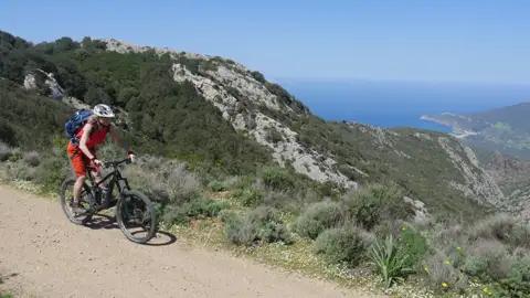 Mountainbiker auf einem Pfad mit Blick auf das Meer.