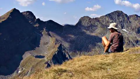 Wanderer pausiert auf einem Berggipfel und betrachtet die Berglandschaft.