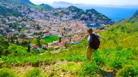 Wanderer auf einem Hügel mit Blick auf eine Küstenstadt und das Meer.