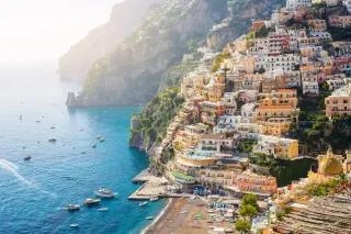 Bunte Häuser an den Hängen einer Steilküste mit Strand und Meer im Vordergrund