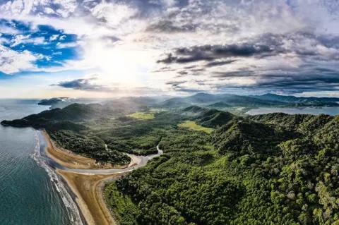 Luftaufnahme von der Küste von Costa Rica mit Meer, Strand und Regenwald unter blauem Himmel