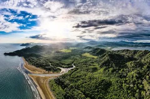 Luftaufnahme von der Küste von Costa Rica mit Meer, Strand und Regenwald unter blauem Himmel