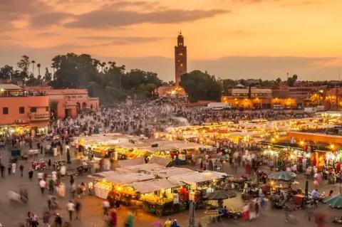 Buntes Treiben auf einem Markplatz in der Abendstimmung mit vielen Lichtern