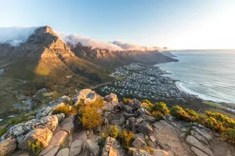Blick von oben über die Küste bei Kapstadt. An der Küste sind viele Häuser zu sehen.