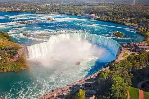 Blick von oben auf ein großes Wasserbecken in das Wasserfälle hineinfließen.