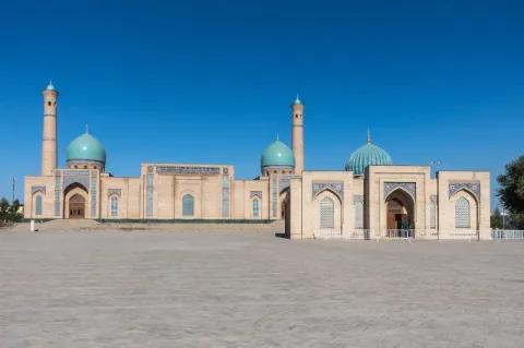 Blick auf einen niedrigen, hellen Gebäudekomplex mit blauen glockenförmigen Dächern.