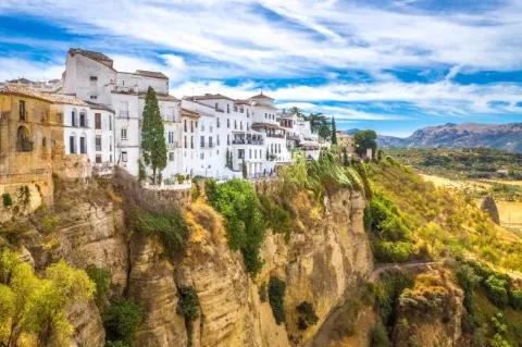 Ein Dorf mit weiß gestrichenen Häusern ist direkt an den Abgrund einer felsigen Schlucht gebaut.