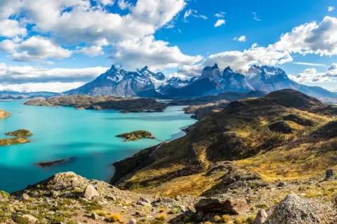 Blick über Seelandschaft auf spitzige, schneebedeckte Gipfel im Hintergrund.
