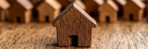 Ein kleines geschnitztes Holzhaus steht auf einer Holzunterlage.