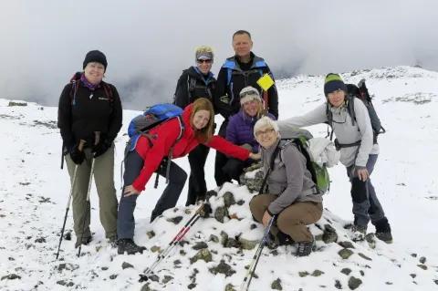 Sieben Wanderer im Schnee posieren für das Foto. Die Sicht ist durch dicken Nebel versperrt.
