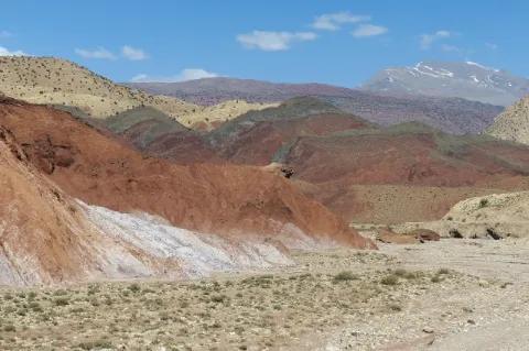 Auf einer Hochebene sind bunte Gipfel. Die Landschaft ist weitestgehend trocken.