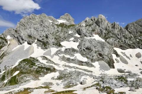 Eine Berglandschaft mit Schneefeldern. Die Felsen sind grau. Der Himmel ist blau.
