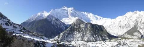 Mehrere schneebedeckte Berggipfel reihen sich aneinander. Der Himmel ist blau.