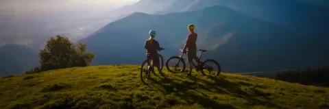 Zwei Frauen auf Mountainbikes unterhalten sich und schauen sich den wunderschönen Sonnenuntergang an