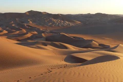 Sanddünen bei Sonnenuntergang unter leicht blauem Himmel