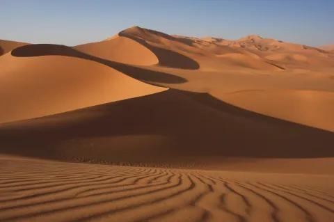 Dünenlandschaft mit Schattenspiel unter blauem Himmel