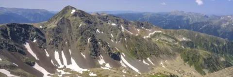 Karge Berglandschaft mit einzelnen Schneefeldern unter blauem Himmel