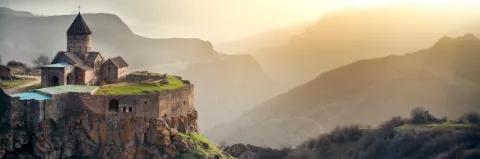 Alte Klosteranlage steht an der Felskante von einem Berg bei trübem Sonnenschein