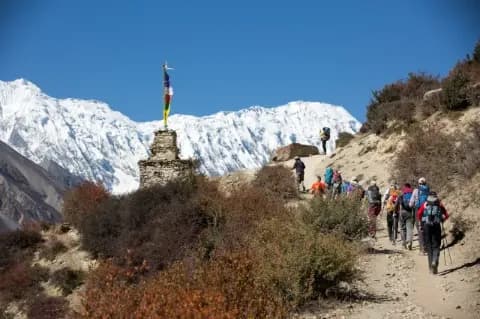 Trekkinggruppe läuft auf Wanderpfad zwischen kargen Sträuchern hinauf zum Aussichtspunkt