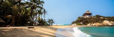 Palmengesäumter Sandstrand, Meer und kleinem bewachsenem Hügel mit einer Hütte