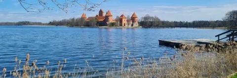 Blick vom Ufer eines blauen Sees auf eine Insel mit einer Burg